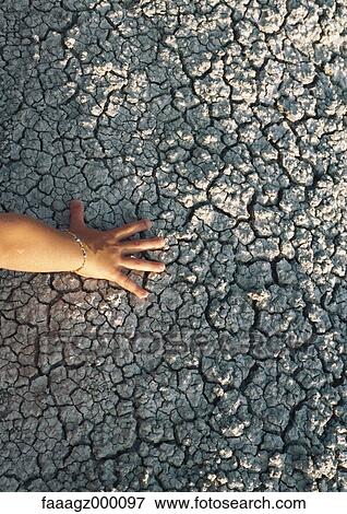Hand touching cracked soil View Large Photo Image Stock Photo - Hand touching cracked soil. Fotosearch