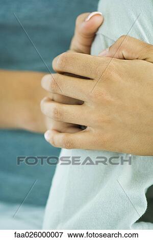 Hands clasping arm, cropped view View Large Photo Image Stock Photo - Hands clasping arm, cropped view. Fotosearch