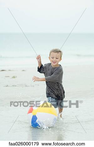 Little boy chasing beach ball at the beach, full length View Large Photo Image Stock Photo - Little boy chasing beach ball at the beach, full length. Fotosearch