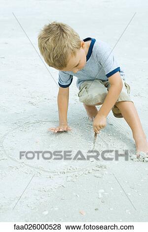 Little boy crouching at the beach, drawing in sand with stick View Large Photo Image Stock Photo - Little boy crouching at the beach, drawing in sand with stick. Fotosearch
