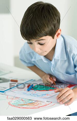 Stock Image - Little boy looking down at crayon drawing on table with wide eyes. Fotosearch
