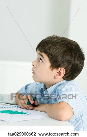 Little boy sitting at table, holding crayon, looking up View Large Photo Image Stock Image - Little boy sitting at table, holding crayon, looking up. Fotosearch