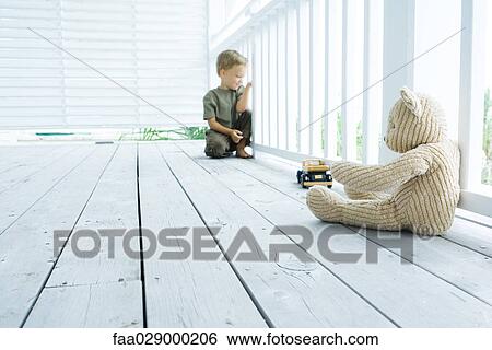 Little boy sitting on porch near teddy bear and toy car, looking through railing View Large Photo Image Stock Photograph - Little boy sitting on porch near teddy bear and toy car, looking through railing. Fotosearch