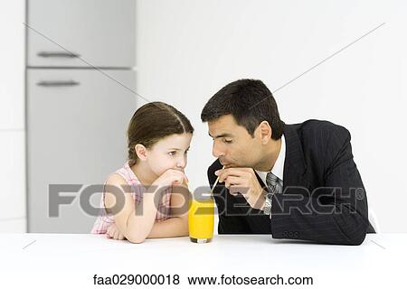 Stock Photo - Little girl and father drinking from glass of juice together. Fotosearch