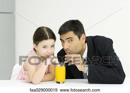Little girl and father drinking from glass of juice with straws, looking at camera View Large Photo Image Stock Photo - Little girl and father drinking from glass of juice with straws, looking at camera. Fotosearch