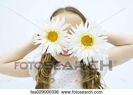 Little girl holding gerbera daisies in front of eyes, smiling, portrait View Large Photo Image Stock Photograph - Little girl holding gerbera daisies in front of eyes, smiling, portrait. Fotosearch