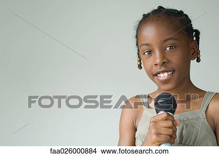 Little girl holding microphone, smiling at camera, portrait View Large Photo Image Picture - Little girl holding microphone, smiling at camera, portrait. Fotosearch