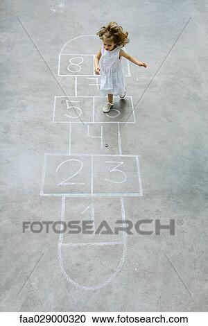 Stock Image - Little girl playing hopscotch, high angle view. Fotosearch