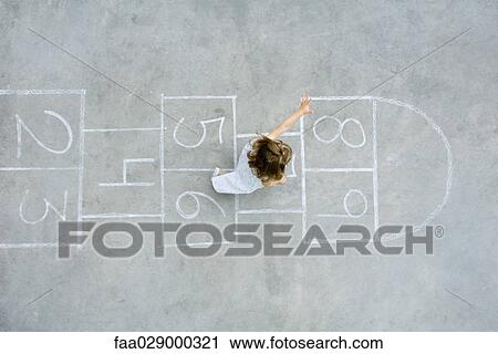 Stock Image - Little girl playing hopscotch, overhead view. Fotosearch