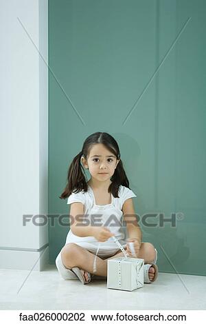 Little girl sitting on the ground, tying ribbon on gift, looking at camera View Large Photo Image Stock Image - Little girl sitting on the ground, tying ribbon on gift, looking at camera. Fotosearch