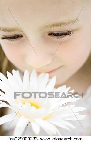 Stock Image - Little girl smelling gerbera daisy, close-up. Fotosearch