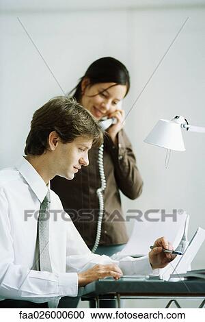 Male and female colleagues looking at laptop computer together, man pointing with pen, woman holding phone View Large Photo Image Stock Image - Male and female colleagues looking at laptop computer together, man pointing with pen, woman holding phone. Fotosearch