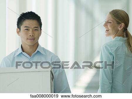 Man carrying boxes in hallway, female colleague watching View Large Photo Image Stock Photo - Man carrying boxes in hallway, female colleague watching. Fotosearch