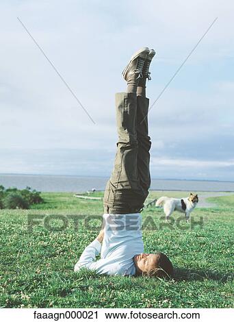 Man doing shoulder stand in grass, dog in background, portrait View Large Photo Image Stock Image - Man doing shoulder stand in grass, dog in background, portrait. Fotosearch