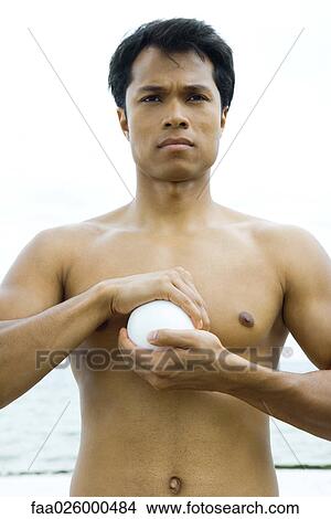 Man holding ball in cupped hands, topless, looking away View Large Photo Image Picture - Man holding ball in cupped hands, topless, looking away. Fotosearch