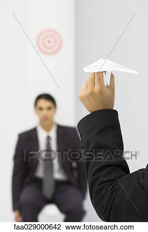 Man holding paper airplane, aiming at target of colleague's head, cropped view View Large Photo Image Stock Image - Man holding paper airplane, aiming at target of colleague's head, cropped view. Fotosearch