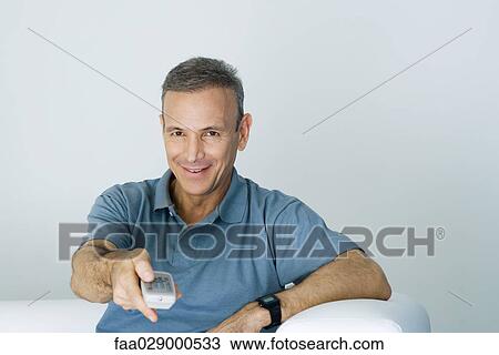Man holding remote control, smiling at camera View Large Photo Image Stock Image - Man holding remote control, smiling at camera. Fotosearch
