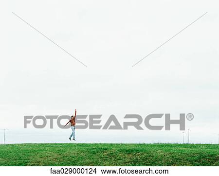 Man jumping in field, mid-distance View Large Photo Image Picture - Man jumping in field, mid-distance. Fotosearch