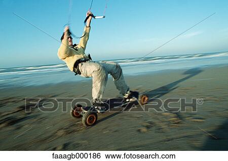 Stock Photograph - Man kitesurfing on beach. Fotosearch