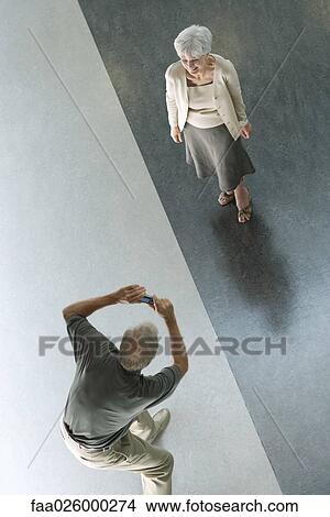 Man photographing wife with digital camera, viewed from directly above View Large Photo Image Picture - Man photographing wife with digital camera, viewed from directly above. Fotosearch
