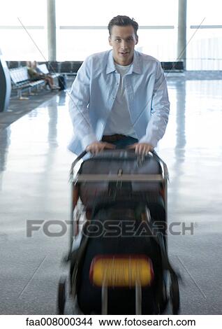 Man pushing luggage cart in airport View Large Photo Image Picture - Man pushing luggage cart in airport. Fotosearch