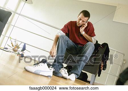 Man putting on shoes and talking on phone View Large Photo Image Picture - Man putting on shoes and talking on phone. Fotosearch