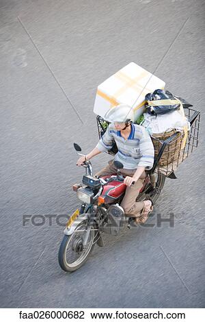 Man riding moped loaded with boxes, high angle view View Large Photo Image Stock Image - Man riding moped loaded with boxes, high angle view. Fotosearch