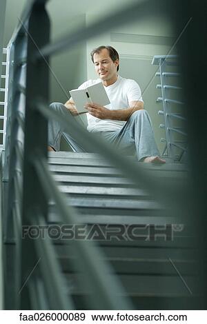 Man sitting at top of staircase reading book, selective focus View Large Photo Image Stock Photo - Man sitting at top of staircase reading book, selective focus. Fotosearch