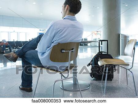 Stock Image - Man sitting in chair in airport, rear view. Fotosearch