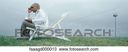 Stock Image - Man sitting in deck chair. Fotosearch