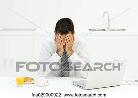 Man sitting next to breakfast and laptop, covering face with hands View Large Photo Image Stock Image - Man sitting next to breakfast and laptop, covering face with hands. Fotosearch