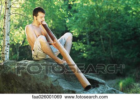 Man sitting outdoors, playing didgeridoo, eyes closed View Large Photo Image Stock Photo - Man sitting outdoors, playing didgeridoo, eyes closed. Fotosearch