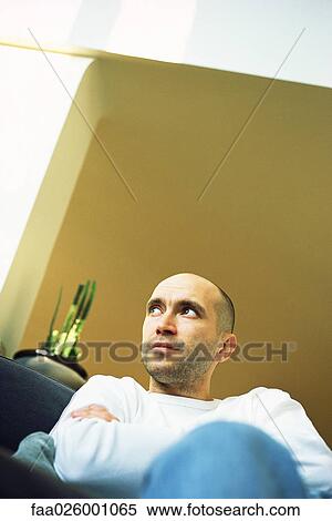 Man sitting with arms folded, looking away, low angle view View Large Photo Image Stock Photography - Man sitting with arms folded, looking away, low angle view. Fotosearch