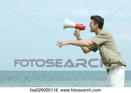 Man standing by the sea, shouting into megaphone, side view View Large Photo Image Stock Photo - Man standing by the sea, shouting into megaphone, side view. Fotosearch