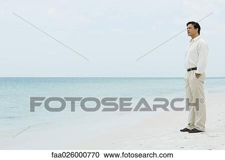 Man standing on beach, looking at view View Large Photo Image Stock Image - Man standing on beach, looking at view. Fotosearch