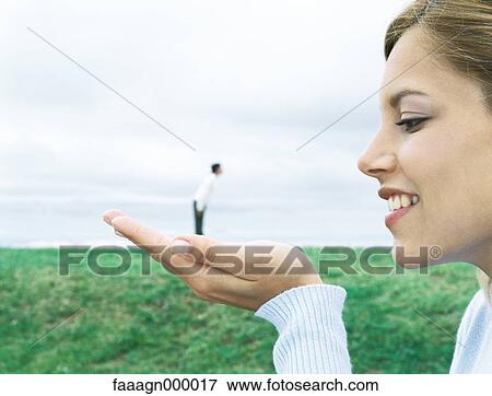 Man standing on woman's hand, optical illusion View Large Photo Image Stock Photo - Man standing on woman's hand, optical illusion. Fotosearch