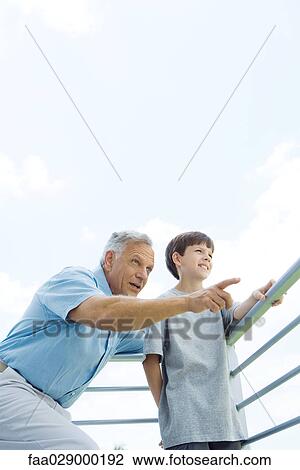 Man standing with arm around grandson's shoulder, pointing, both looking away, low angle view View Large Photo Image Stock Image - Man standing with arm around grandson's shoulder, pointing, both looking away, low angle view. Fotosearch
