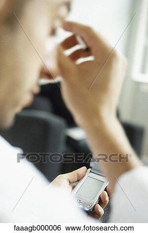 Stock Photograph - Man using cell phone, rubbing head. Fotosearch