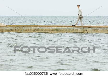 Man walking on jetty, looking toward camera View Large Photo Image Stock Photograph - Man walking on jetty, looking toward camera. Fotosearch