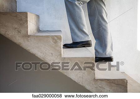 Stock Photo - Man walking up staircase, side view, cropped. Fotosearch