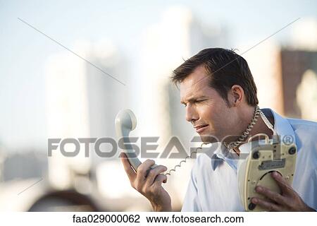 Man wrapping landline phone cord around neck, looking at receiver View Large Photo Image Stock Image - Man wrapping landline phone cord around neck, looking at receiver. Fotosearch