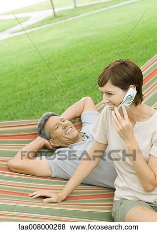 Mature couple lounging in hammock, woman using cell phone View Large Photo Image Stock Photo - Mature couple lounging in hammock, woman using cell phone. Fotosearch