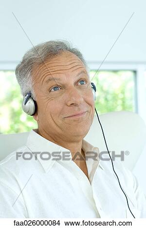 Picture - Mature man listening to headphones, smiling, looking up. Fotosearch