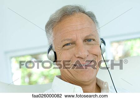 Mature man listening to headphones, smiling at camera, close-up View Large Photo Image Stock Image - Mature man listening to headphones, smiling at camera, close-up. Fotosearch