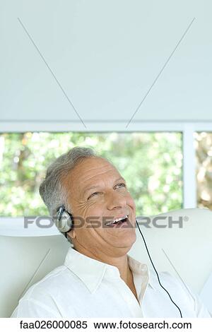Mature man listening to headphones, laughing, looking up View Large Photo Image Stock Photography - Mature man listening to headphones, laughing, looking up. Fotosearch