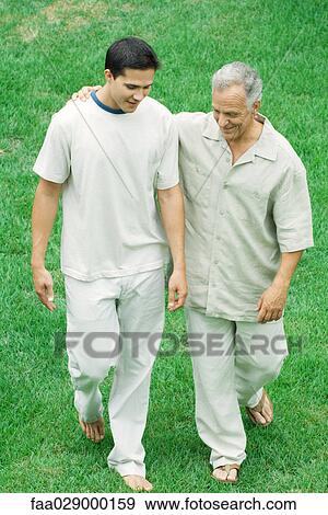 Mature man walking with arm around adult son's shoulder outdoors, both looking down View Large Photo Image Stock Photo - Mature man walking with arm around adult son's shoulder outdoors, both looking down. Fotosearch