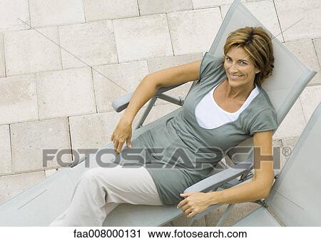 Stock Image - Mature woman in lounge chair, high angle view. Fotosearch