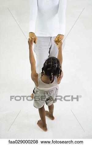 Mother and daughter standing face to face, holding hands, high angle view, cropped View Large Photo Image Stock Photo - Mother and daughter standing face to face, holding hands, high angle view, cropped. Fotosearch