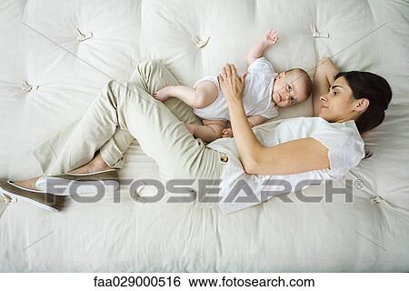 Mother and infant lying together on bed, high angle view View Large Photo Image Stock Photograph - Mother and infant lying together on bed, high angle view. Fotosearch