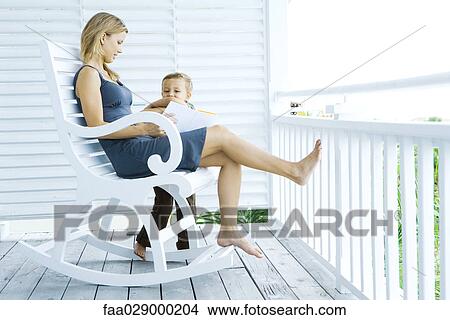 Picture - Mother and son reading book together on porch. Fotosearch